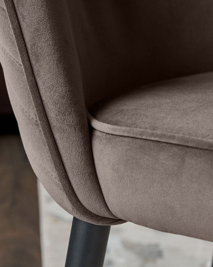 Serena velvet dining chair in mocha, close-up detail of curved armrest and seat upholstery with dark leg base.