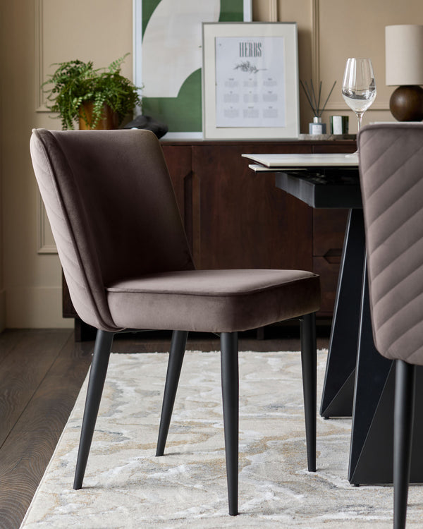 Serena velvet dining chair in mocha, shown at an angle with black tapered legs, displayed in a styled dining room setting.