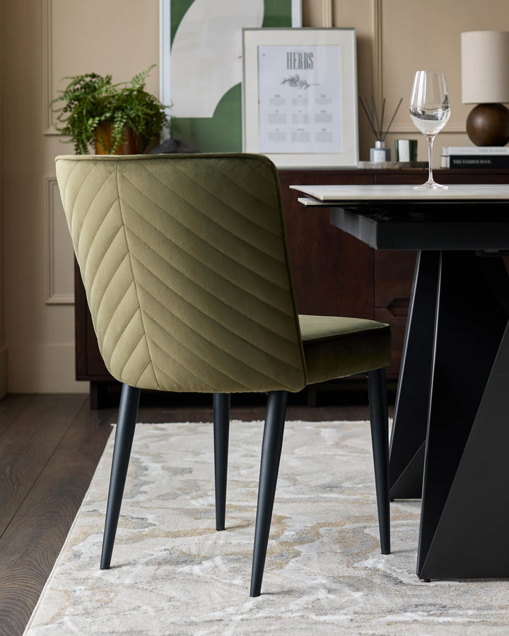 An olive green quilted dining chair with black legs, set beside a table and rug in a dining room setting.