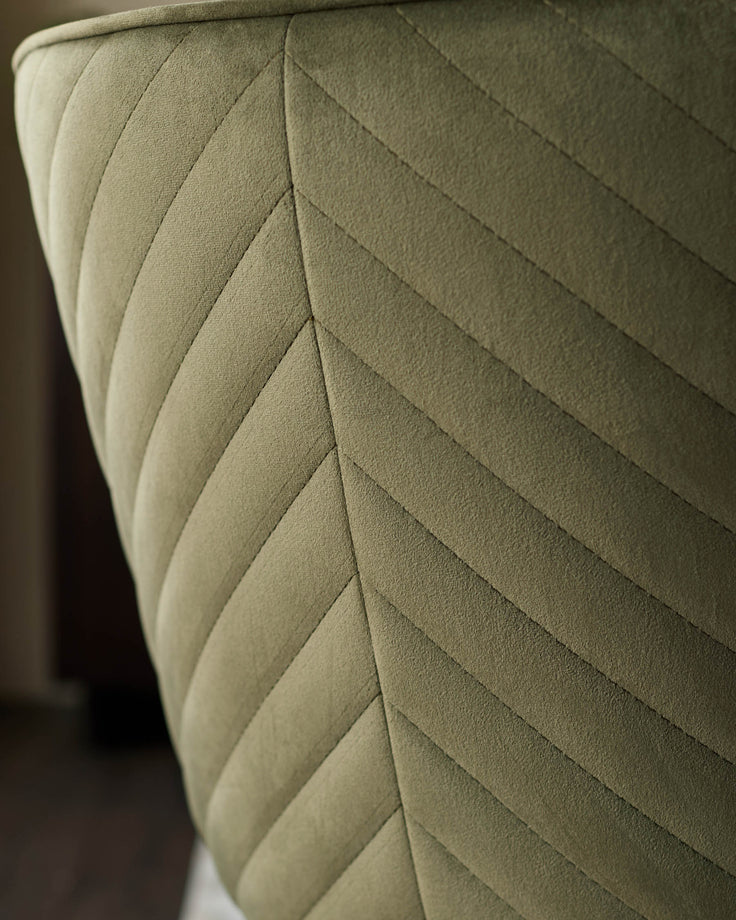 Close-up of a stylish chair back. Olive green, quilted, with a chevron pattern. Comfortable and modern furniture.