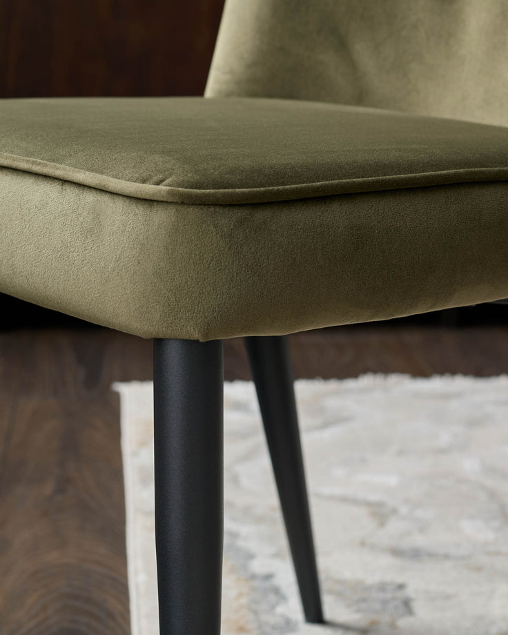 Close-up of an upholstered chair seat with black legs, showcasing the texture and design details.