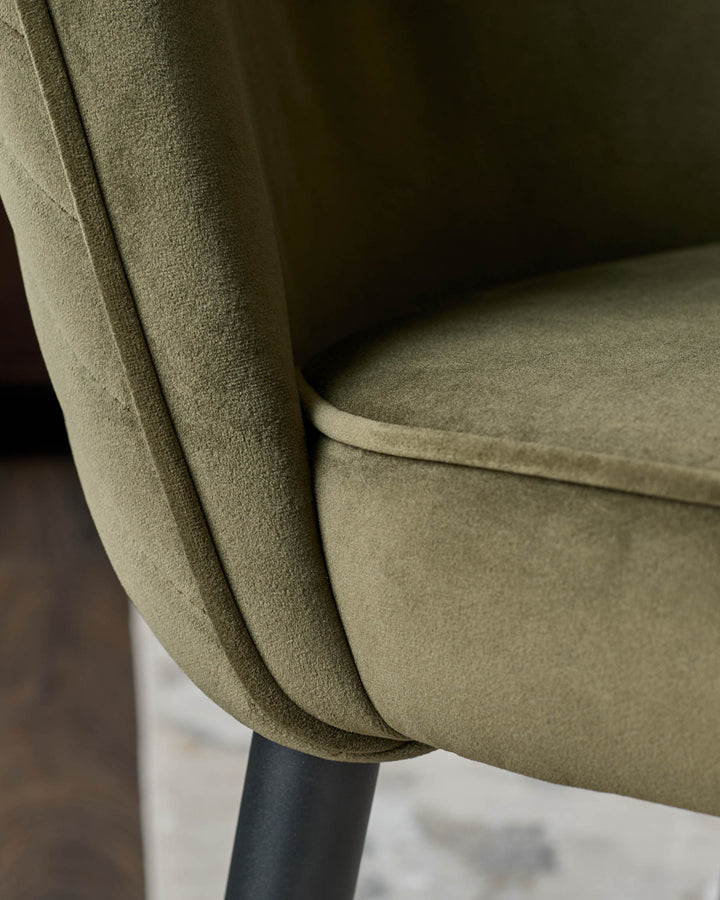 Close-up of a stylish olive green velvet chair with a sleek black leg, perfect for adding a touch of luxury to any dining space.