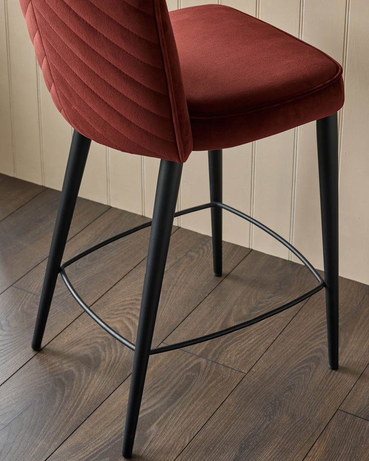 Close-up of a stylish rust-coloured velvet bar stool with black legs and footrest. Modern design for the home.