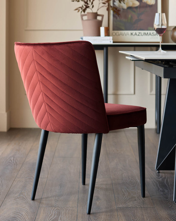 A stylish, claret chair with chevron detailing and dark, elegant legs, sitting in a well-lit dining space.