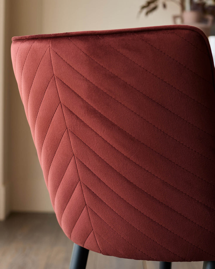 Close-up of a stylish red chair with patterned stitching. Perfect for adding a touch of elegance to your dining space.