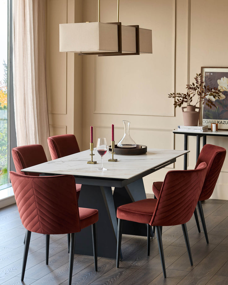 Dining set featuring a modern table with marble effect top and stylish, deep red velvet chairs.