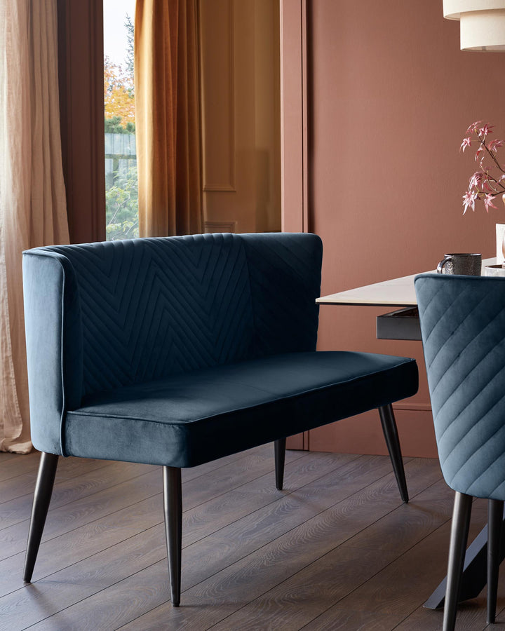 A blue velvet dining bench and chair sit next to a table, all with sleek, dark legs.