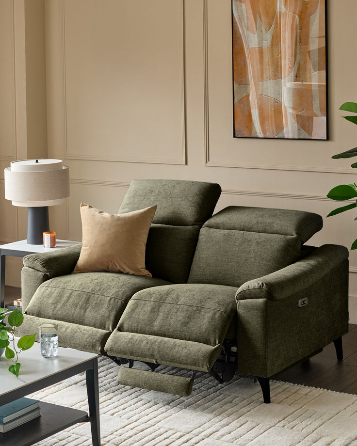 Dark green fabric 2-seater recliner sofa with footrests extended, positioned in a neutral living room with beige walls and modern decor.