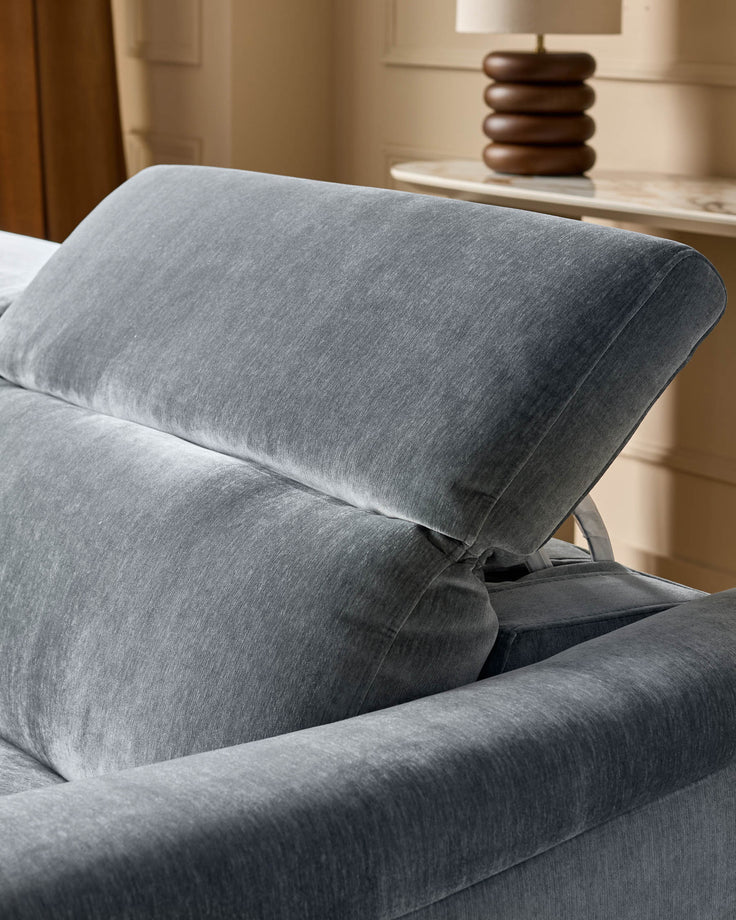 Blue-grey fabric corner recliner sofa with rolled armrest and reclined backrest, shown in bedroom setting.