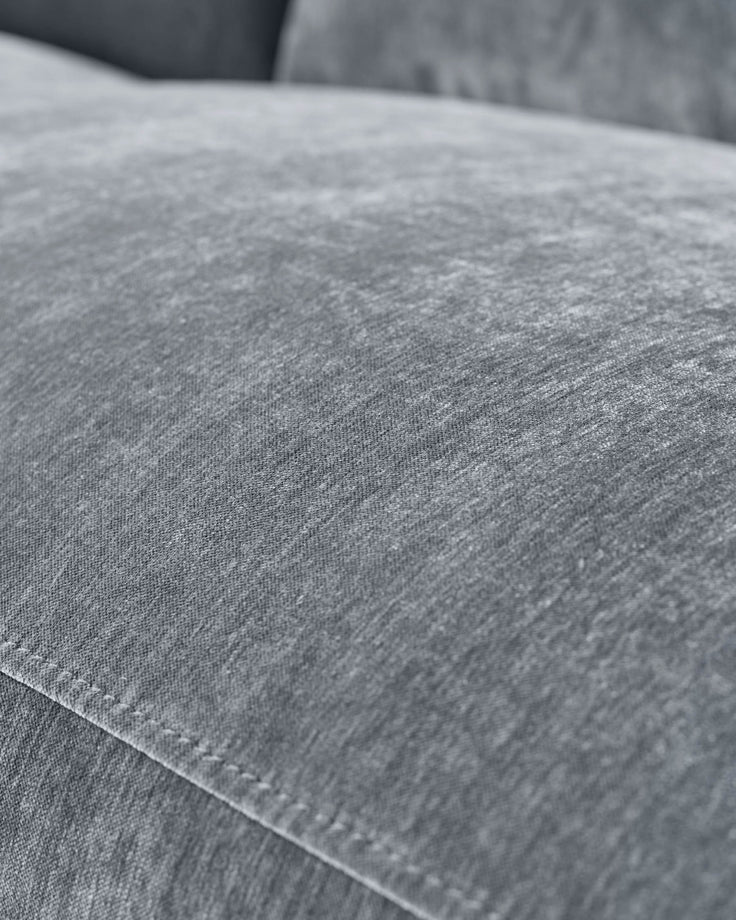 Close-up of blue-grey fabric texture on recliner sofa showing weave detail and stitching.