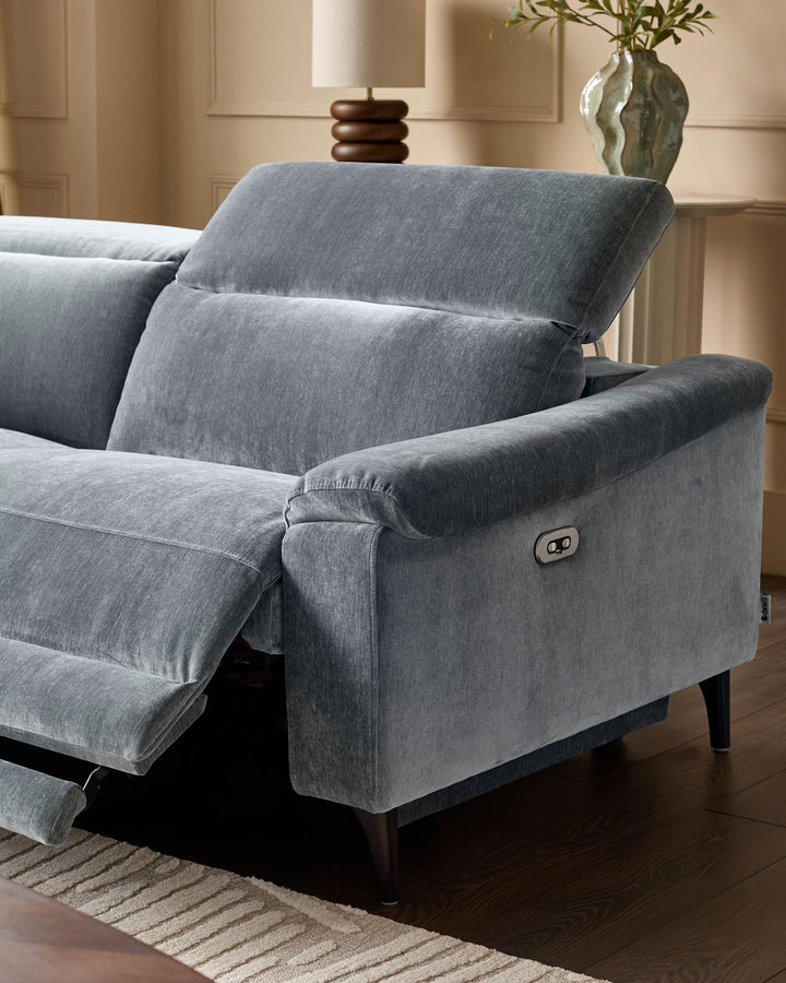 Serene left small corner recliner sofa in blue-grey fabric, shown at an angle displaying the rolled armrest and recline mechanism button.