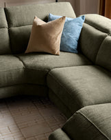 Serene left chaise recliner sofa in dark green chenille with decorative pillows in beige and blue.