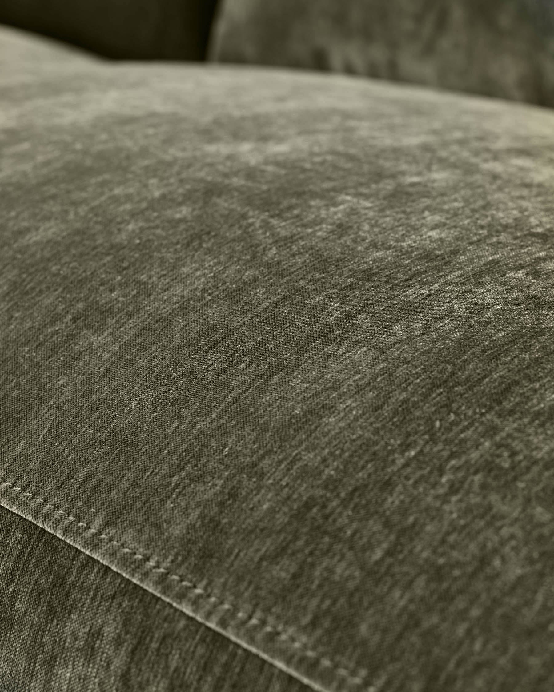 Close-up of dark green fabric texture on Serene 3-seater recliner sofa, showing weave detail and stitching.