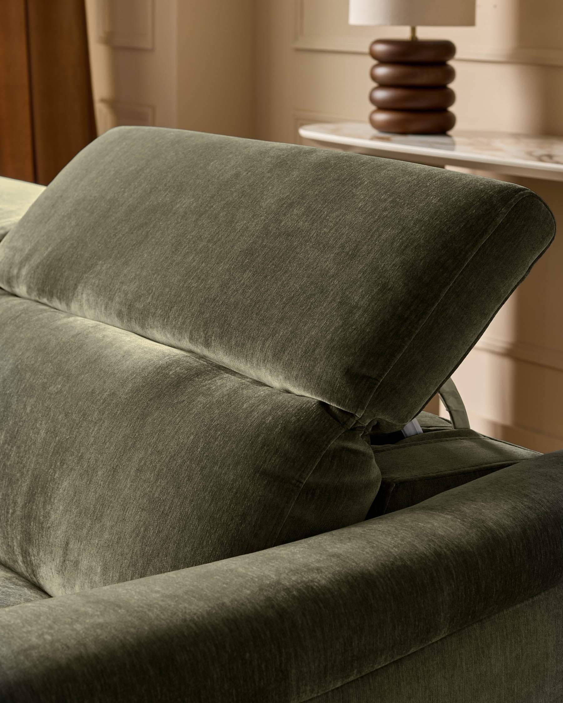 Dark green fabric left-hand corner recliner sofa with padded headrest and angled recline mechanism, viewed from side.