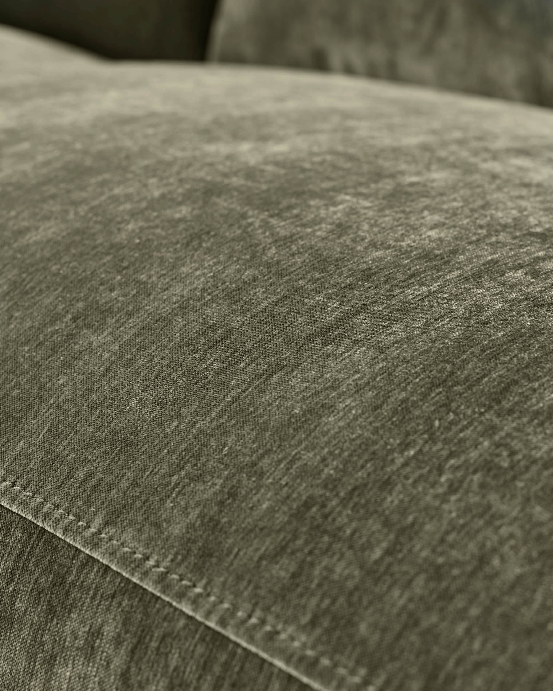 Close-up of dark green fabric texture on Serene left small corner recliner sofa, showing weave detail and stitching.
