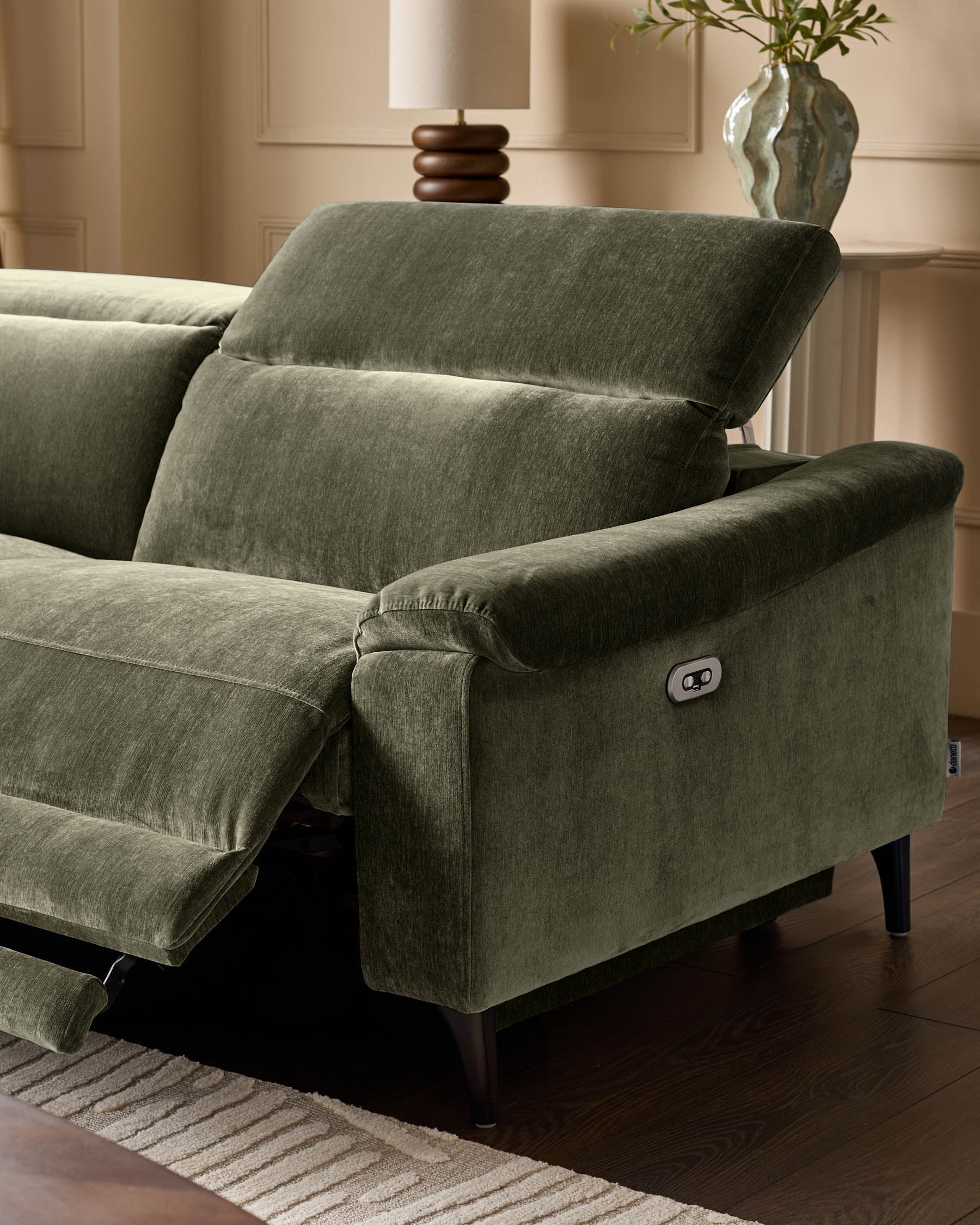 Dark green fabric left-corner recliner with rolled armrests, power recline button visible, angled view in neutral room setting.