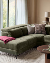 Serene left small corner recliner sofa in dark green fabric, styled with decorative pillows and throw blanket in a bright living room.