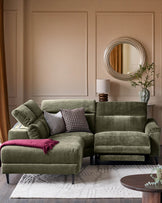 Serene left small corner recliner sofa in dark green fabric, displayed in a styled living room setting with cushions and throw blanket.