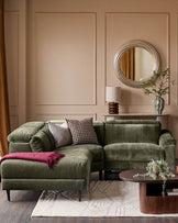 Serene left small corner recliner sofa in dark green fabric, displayed in a modern living room setting with neutral walls and wooden accents.