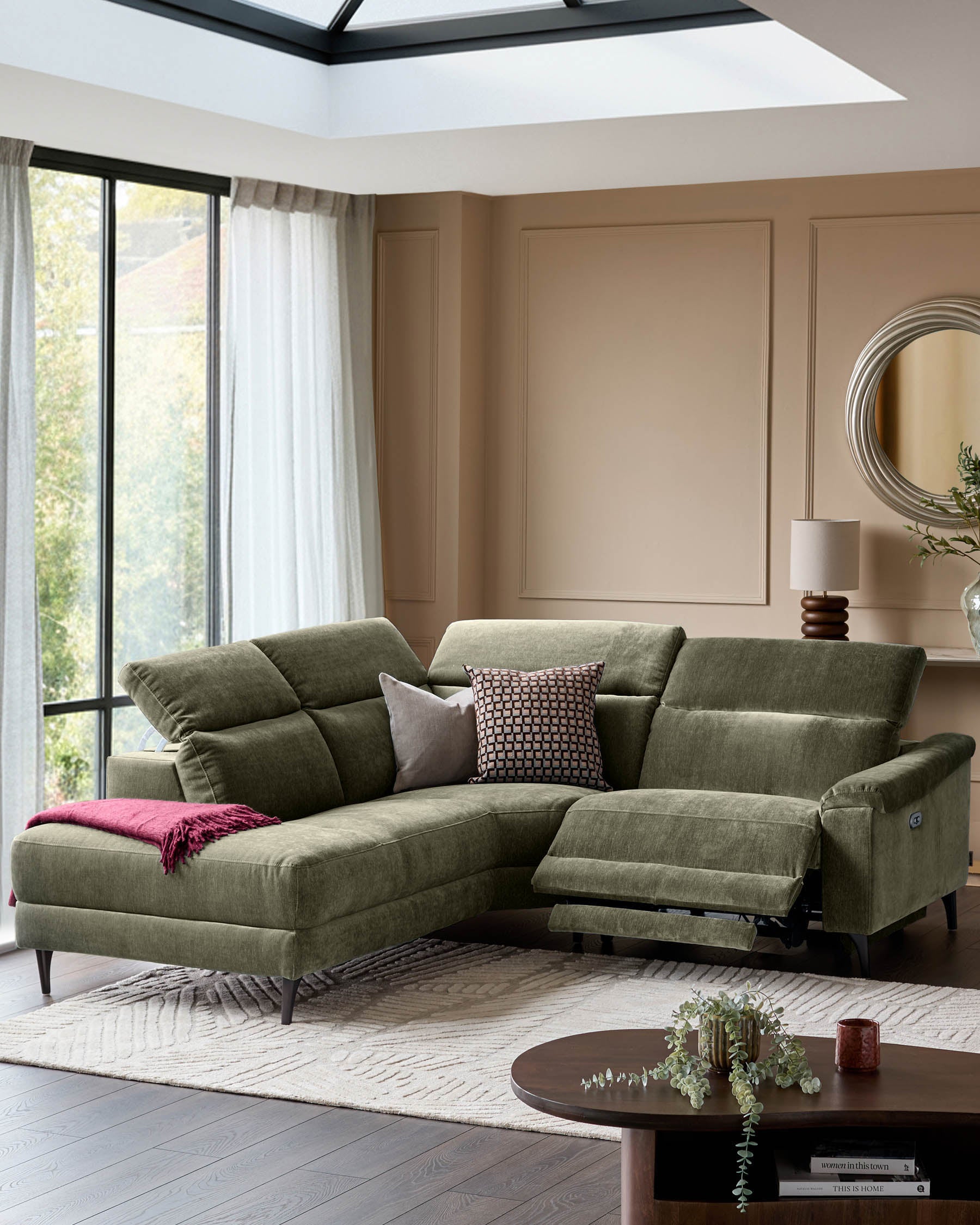 Serene left small corner recliner sofa in dark green fabric with reclined footrest, positioned in a modern living room with skylight.