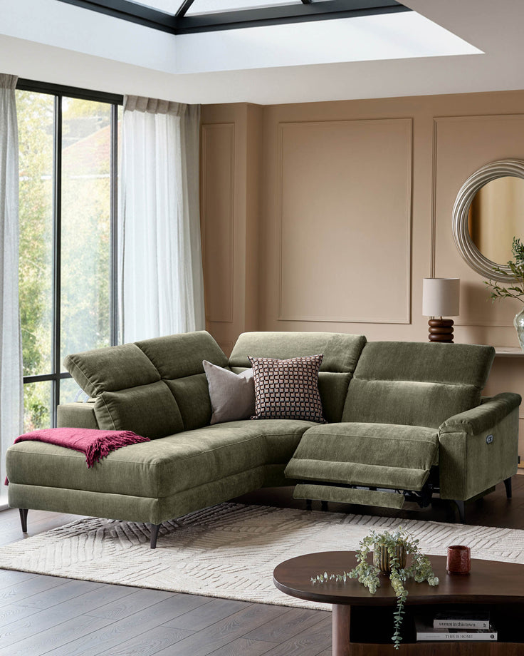 Serene left small corner recliner sofa in dark green fabric with reclined footrest, positioned in a modern living room with skylight.