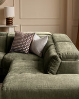 Serene right small corner recliner sofa in dark green fabric with decorative pillows in a neutral beige interior setting.