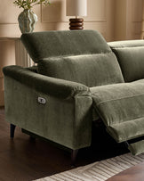 Dark green fabric reclining corner sofa with extended footrest, showing white control button on armrest, dark wooden legs.