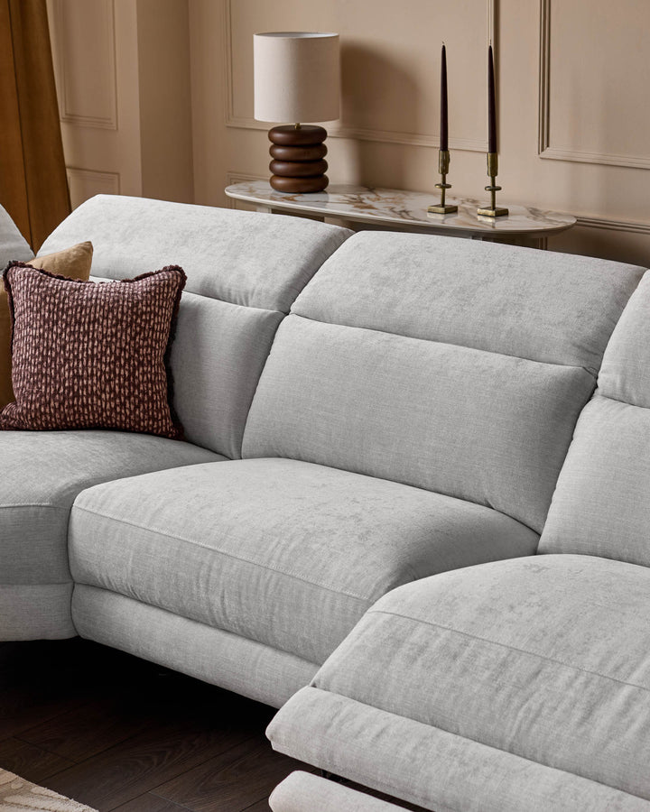 Serene left small corner recliner sofa in light grey fabric, shown in a styled living room setting with burgundy pillow and marble console table.