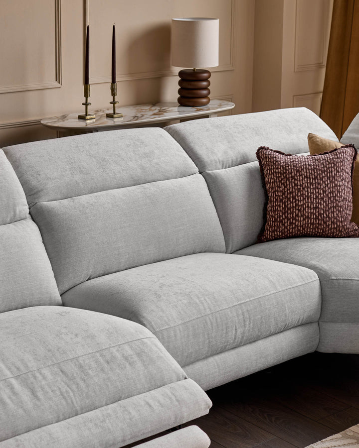 Serene right small corner recliner sofa in light grey fabric, showing quilted cushioning and burgundy accent pillow in styled living room.