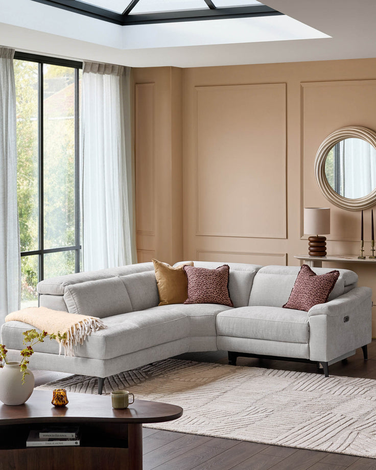 Serene left small corner recliner sofa in light grey fabric, displayed in a modern living room with neutral decor and skylight.