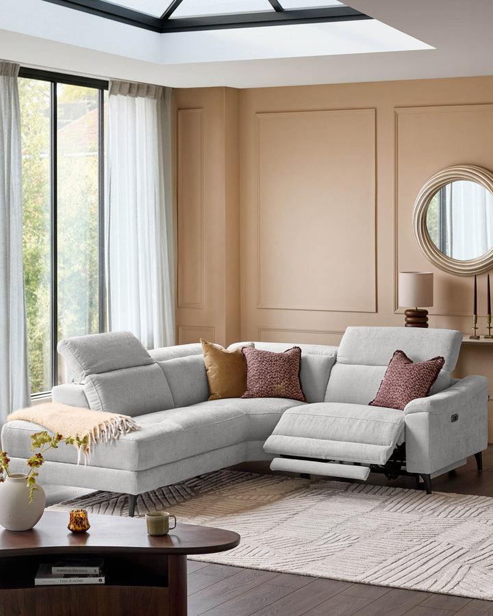 Light grey left-facing corner recliner sofa with extended footrest in modern living room with beige walls and skylights.