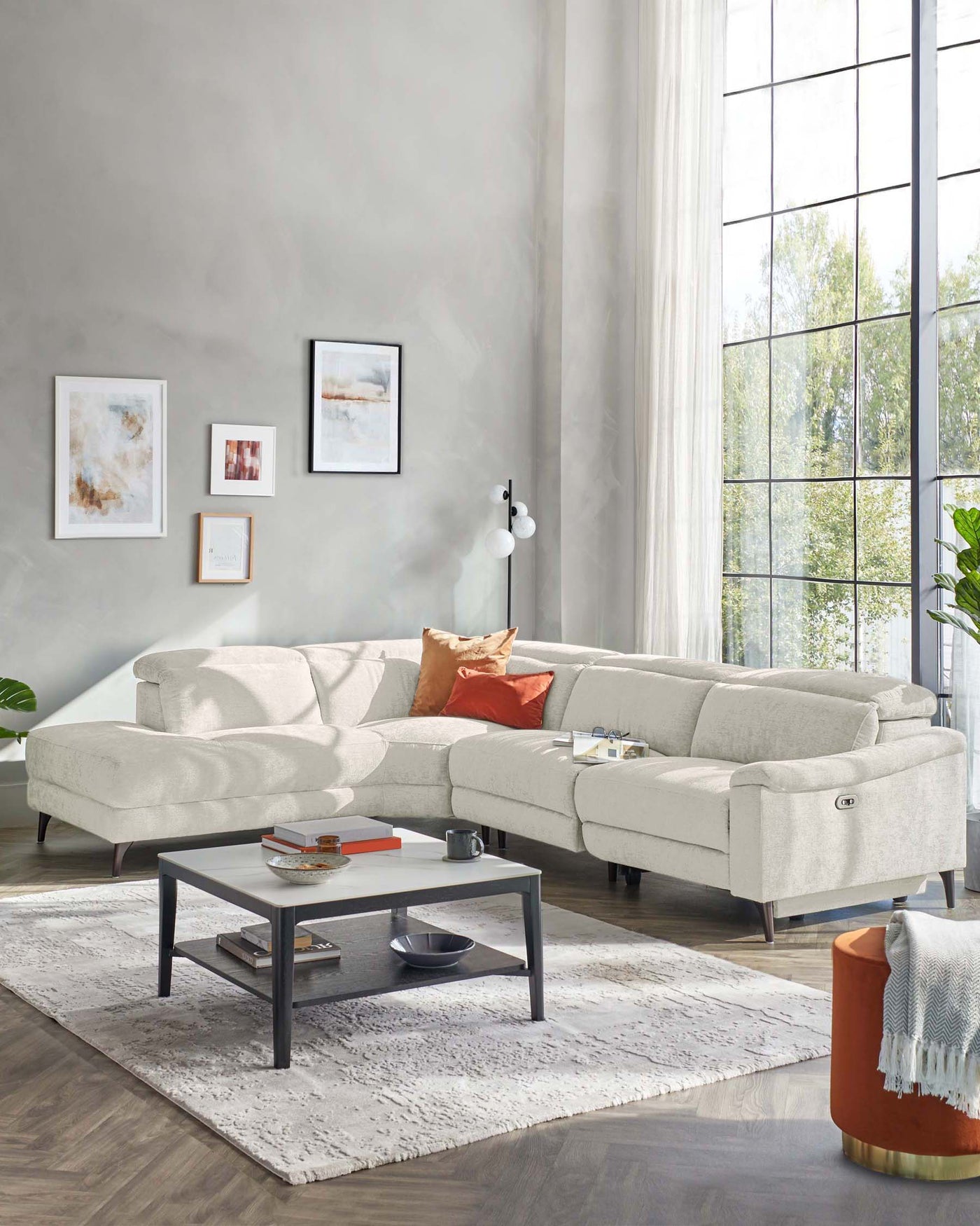 Contemporary light grey sectional sofa with chaise on the right side and a rectangular, two-tiered coffee table with a black frame and grey top, set on a textured white area rug.