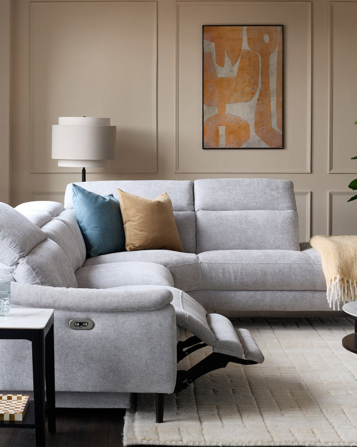 Light grey chenille right-facing chaise recliner sofa with one seat reclined, shown in a styled living room setting.