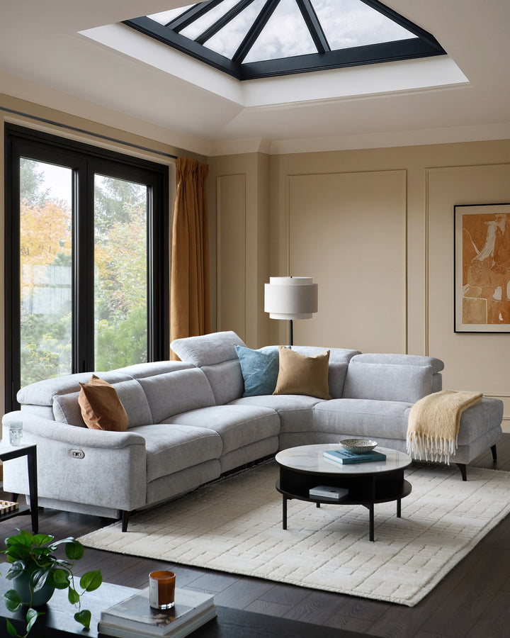 Light grey chenille right chaise recliner sofa in a modern living room setting with skylights and black-framed doors.