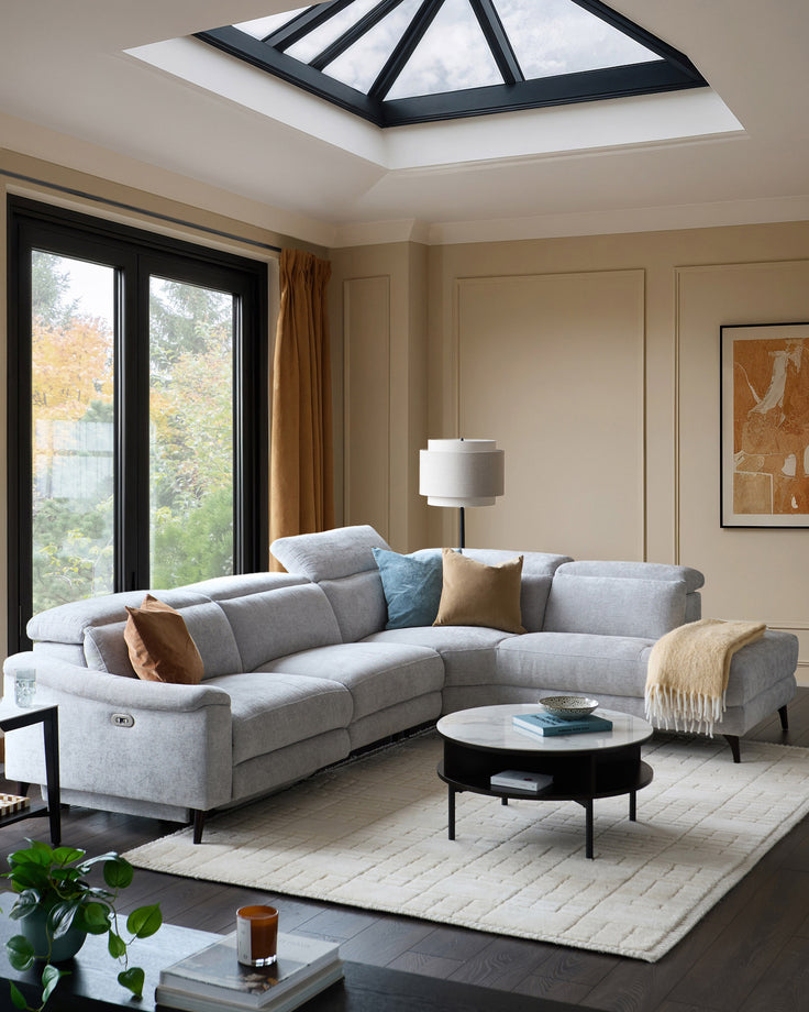 Light grey chenille right chaise recliner sofa in a modern living room setting with skylights and black-framed doors.