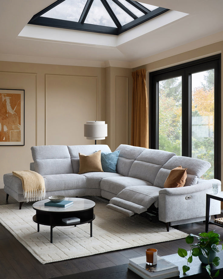 Light grey chenille left chaise recliner sofa with extended footrest in a modern living room with skylight.