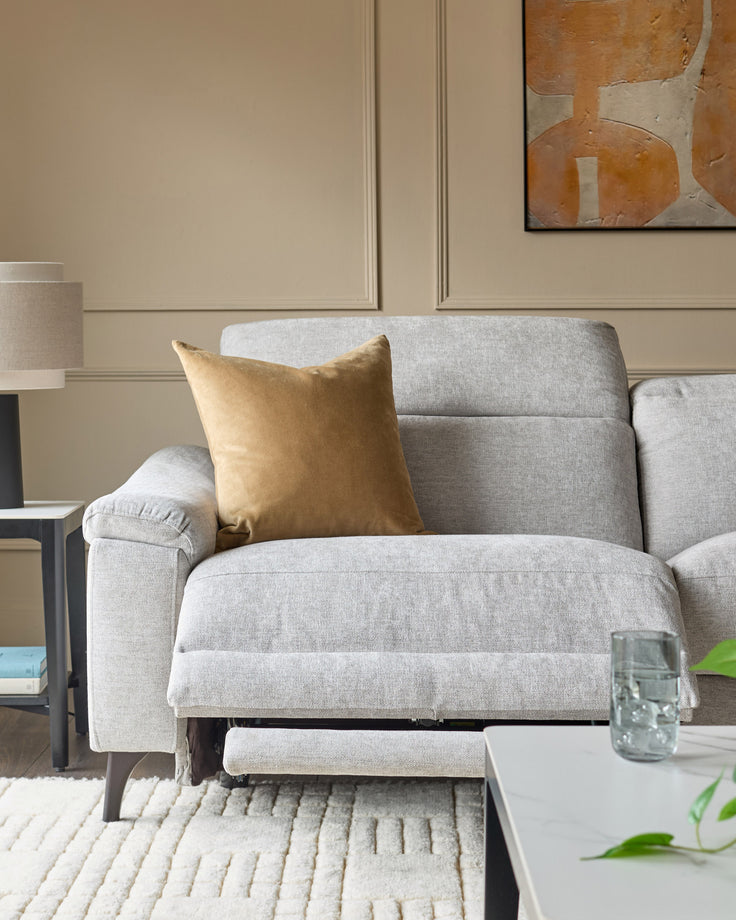 Serene 3-seater light grey fabric recliner sofa with footrest extended, styled with gold cushion in neutral living room.