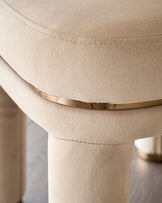 Shay dining chair in champagne velvet, close-up detail of curved backrest and gold metal band accent.