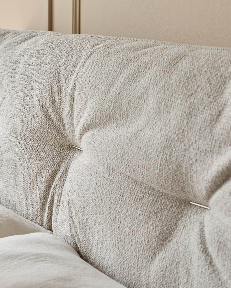 Close-up of a buttoned, upholstered headboard, showcasing its detailed fabric and design.