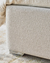 Close up of textured neutral storage bench with soft blanket and geometric rug, showcasing fabric detail and stylish design.