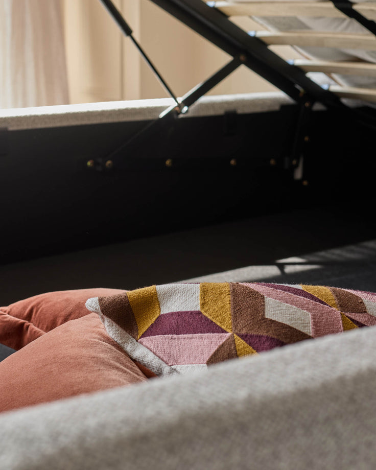 An ottoman storage bed with brown and patterned cushions. Ideal for space-saving, stylish bedroom furniture.