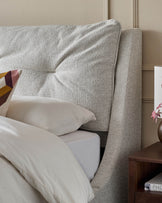 A stylish grey upholstered bed and wooden bedside table, creating a cosy and modern bedroom setting.