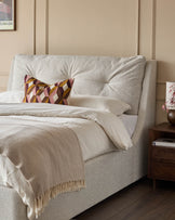 Siesta super king-size ottoman bed in natural fabric with tufted headboard and cream bedding styled with decorative pillows.