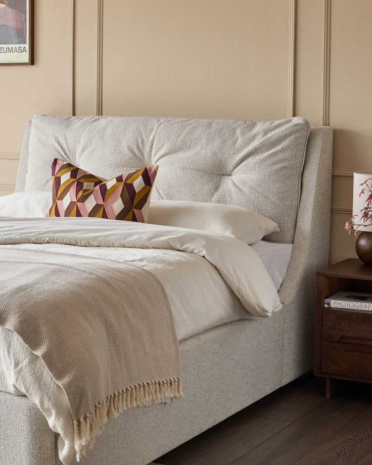 Siesta super king-size ottoman bed in natural fabric with tufted headboard and cream bedding styled with decorative pillows.