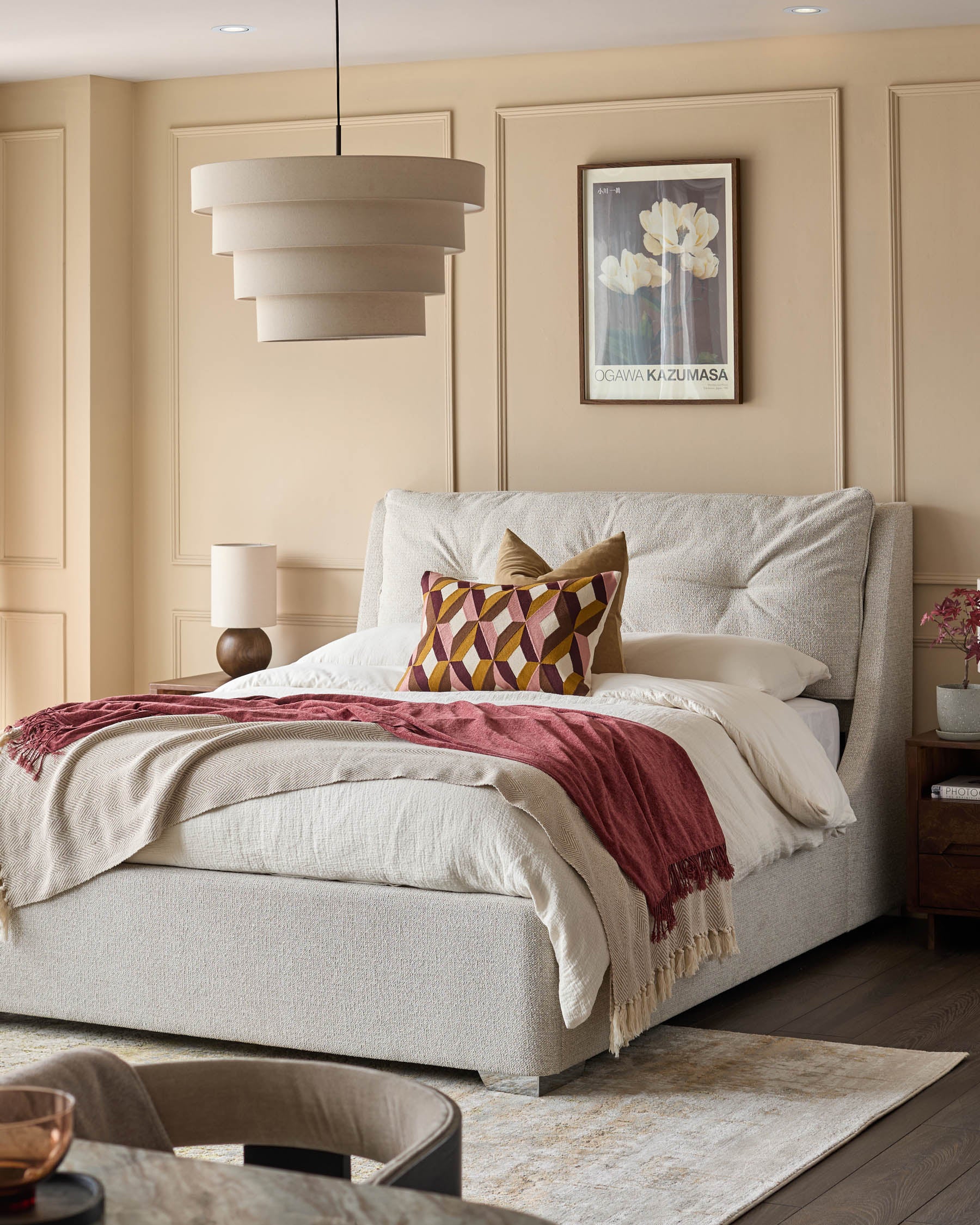 Bedroom with upholstered bed, side table, lamp, and hanging light fixture. Modern design for a cosy and stylish interior.