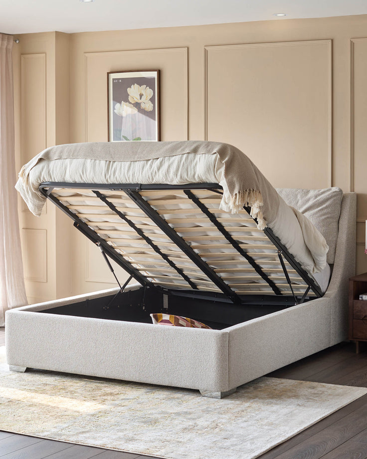 Open-frame, light-beige upholstered storage bed on a patterned cream rug, offering ample storage.