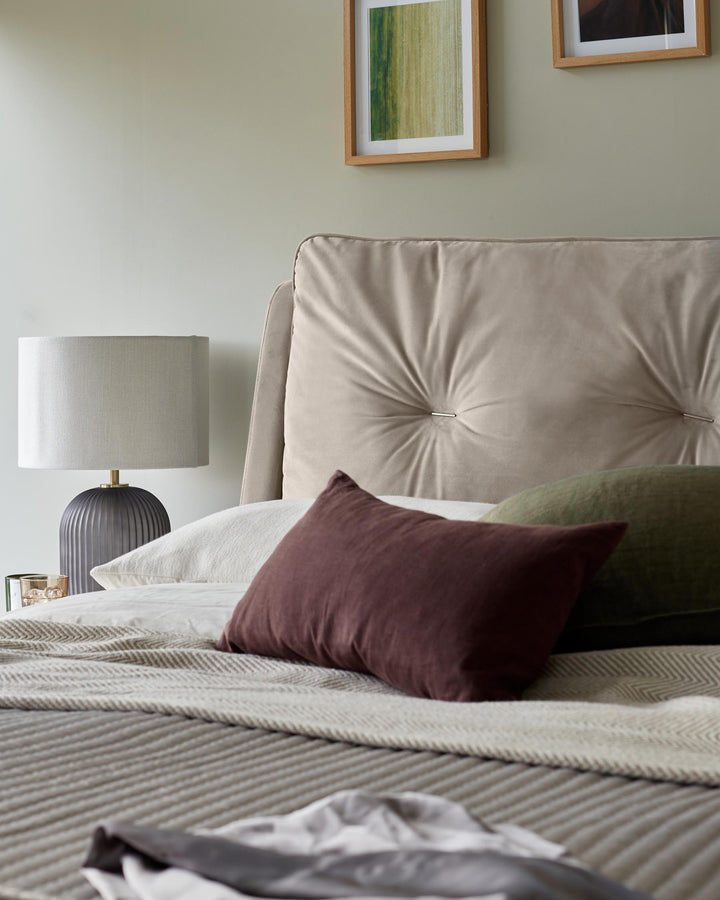 A stylish bedroom setup with a plush headboard, textured throws, and soft cushions for a cosy, inviting ambience.