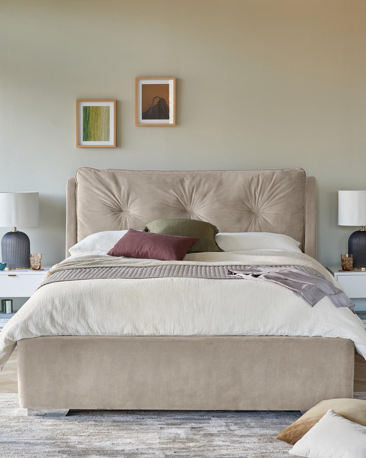 A stylish bedroom featuring a beige upholstered bed, white bedside tables, and neutral-toned artwork, creating a cosy and inviting space.