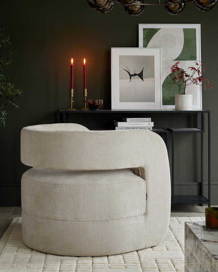 Elegant cream swivel chair with a dark metal console table featuring art prints, candles, and decorative items.