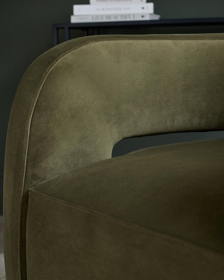 Close-up of a stylish, olive green velvet chair, showcasing its curved back and plush texture.